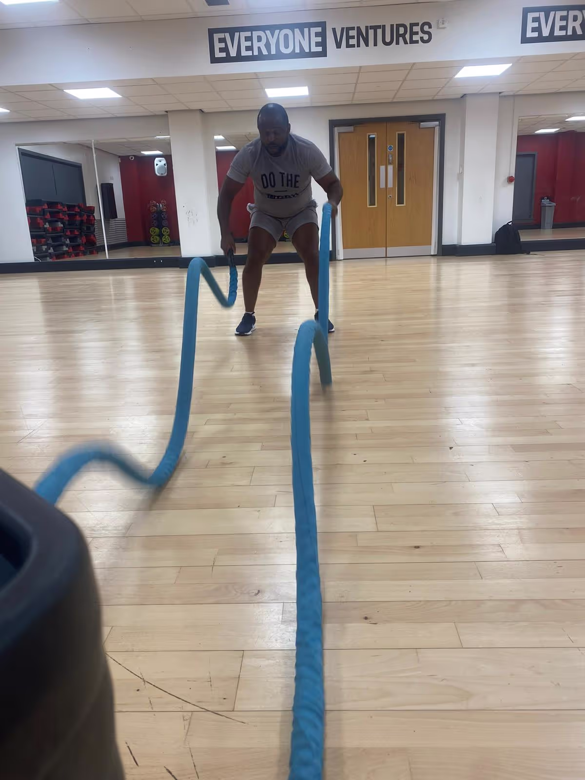Client completing battle rope reps in a gym classroom.