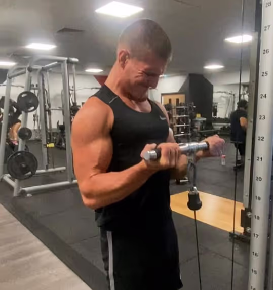 Damien Goring Personal Trainer mid-rep of a biceps exercise using a cable machine.